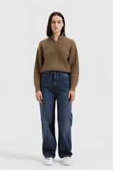 Person wearing a brown ribbed sweater and blue jeans on a white background