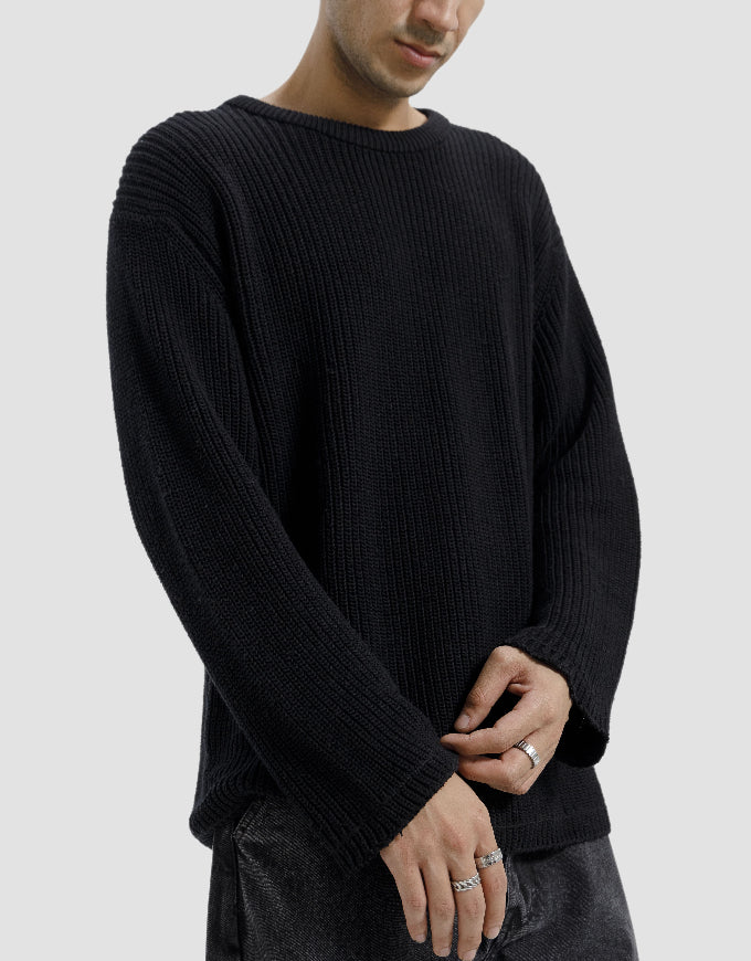 Person wearing a black ribbed sweater on a plain background