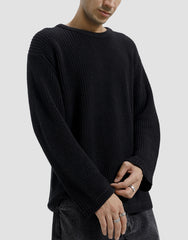 Person wearing a black ribbed sweater on a plain background