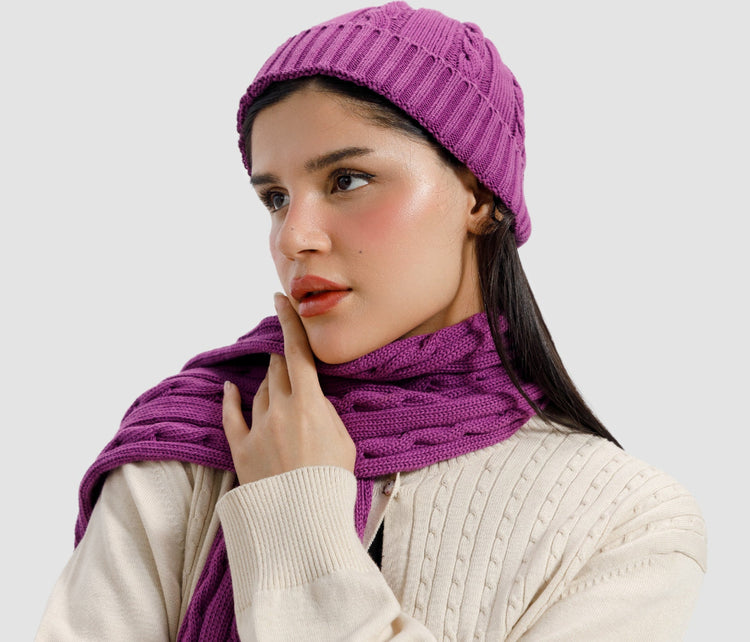 Woman wearing a purple knit hat and scarf on a light gray background